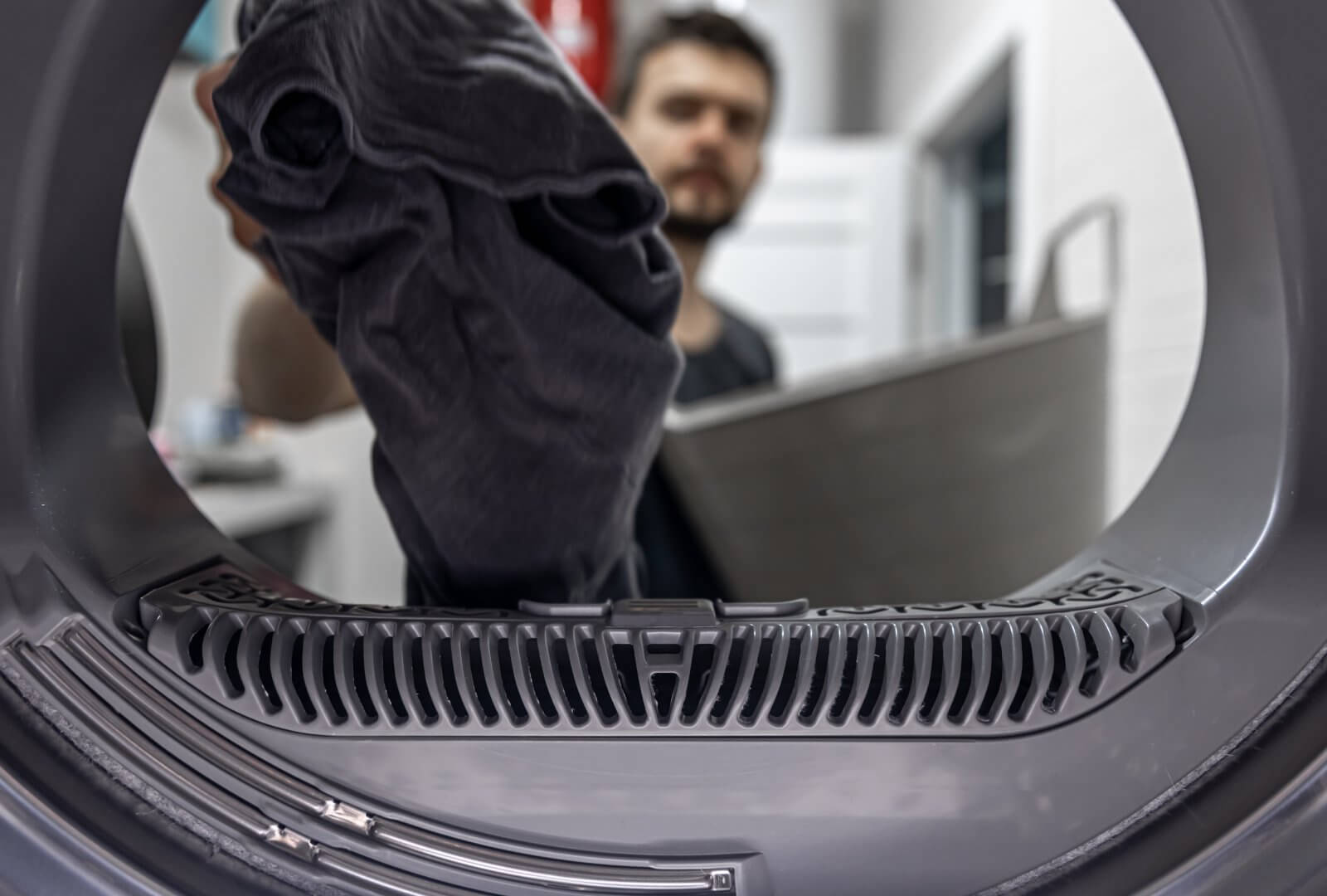 Technician replacing dryer drive belt showing proper routing around drum and pulleys